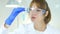 Female scientist holding and looking at blue solution in flask in laboratory