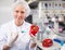 Female scientist injecting reagent from syringe into bell pepper, performing scientific researching of food genetic