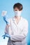 Female scientist with mask holding a transparent pill with fingers in gloves in pharmaceutical research laboratory