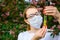 Female scientist in medical mask with test tubes in her hands studies the properties of plants in Botanical garden. Creating