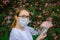 Female scientist in medical mask with test tubes in her hands studies the properties of plants in Botanical garden. Creating