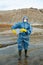 Female scientist in protective coveralls, respirator, rubber gloves and boots