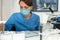 Female scientist in uniform wearing a mask weighs powder on spec