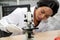 Female Scientist using Microscope in Laboratory. Female Researcher wearing white Coat sitting at Desk and looking at Samples.