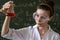 female scientist in white coat and glasses holding laboratory flask with red liquid