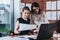 Female secretary looking concerned while her boss checking document sitting at desk in modern office