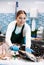 Female seller in apron shows hands fish trout on counter in supermarket