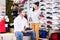 Female seller demonstrating sneakers to customer in sports store