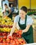 Female seller lays out ripe tomatoes on the counter of grocery supermarket