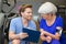 Female senior discussing with gym trainer looking at clipboard