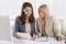 Female senior and junior managers sitting at desk working together in a business team.