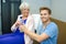 Female senior with water bottle and trainer at gym