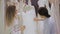 Female shop consultant helps bride chooses dress at shop of wedding fashion. Focus on girl.