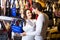 Female shopgirl helping young man to select handbag