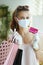 Female shopper with mask, rubber gloves, credit card and bags