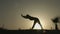 Female silhouette doing body stretching exercises, practicing yoga in sunlight