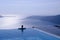 Female silhouette in infinity pool on cliff, Santorini, Greece
