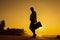 Female Silhouette staying along Ocean Coast with Luggage Bag enjoying scenic View Sea and Sunrise on background. Beach Holiday Co