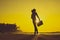 Female Silhouette staying along Ocean Coast with Luggage Bag enjoying scenic View Sea and Sunrise on background. Beach Holiday Co