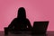 Female silhouette working on laptop sitting at workplace in dark office, shadow business, corruption, night shift