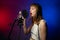 female singer sings into microphone with pop filter in recording studio