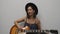 Female singing and playing on guitar. Woman singing lyric song. Young pretty girl in hat emotionally singing and practicing to pla