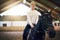 Female sitting astride in indoor riding hall