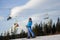 Female skier against ski-lift and forest on a sunny day