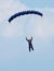 Female sky diver with bright blue open parachute