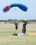 Female skydiver making safe landing on grass with open brightly