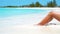 Female slim tanned legs on a white tropical beach. SLOW VIDEO