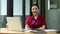 Female smile and looks to camera, arms crossed, sitting in her working space