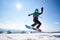 Female snowboarder jumping in air on background of blue sky and snowy mountains on sunny day.