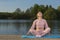 Female Sport Concepts. Relaxing Senior Woman in Sport Outfit Practicing Yoga On Wooden Stage Near Water Outdoor