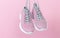 Female sport sneakers for run or fitness hanging on pink background closeup