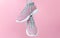 Female sport sneakers for run or fitness hanging on pink background closeup