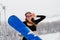 Female in sport wear snowboarder posing in sunglasses with snowboard