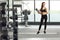 Female in sportswear holding a healthy green shake in a cup and an exercise mat at the gym