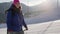 female sporty tourist is walking in ski resort at sunny winter day, rising on top of slope