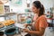 female stall owner in apron checking material shopping on clipboard