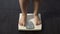 Female standing on home scales to measure weight, obesity, problems with health