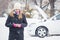 Female standing next to broken car and using mobile assistance smart phone app.