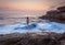 Female standing on shipwreck rock with ocean awash flowing over it