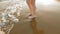 Female stands on wet sand and waves at the beach