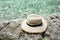 Female straw sunhat on stone. Clean sea. Summer vacation