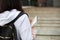 A female student with a black backpack and a notebook in her hands stands on the steps in front of the Institute. Higher education