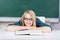 Female Student With Book Leaning On Desk In Classroom