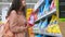 female student is choosing washing powder in supermarket