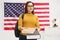 Female student giving books in front of USA flag