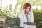 Female Student Outside with Headache Sitting with Books and Back